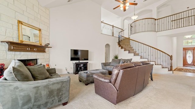 carpeted living room with ceiling fan, a fireplace, and high vaulted ceiling