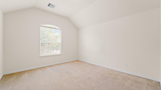 carpeted empty room with vaulted ceiling