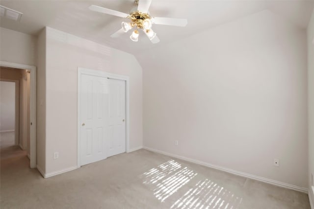 unfurnished bedroom with a closet, light colored carpet, ceiling fan, and lofted ceiling