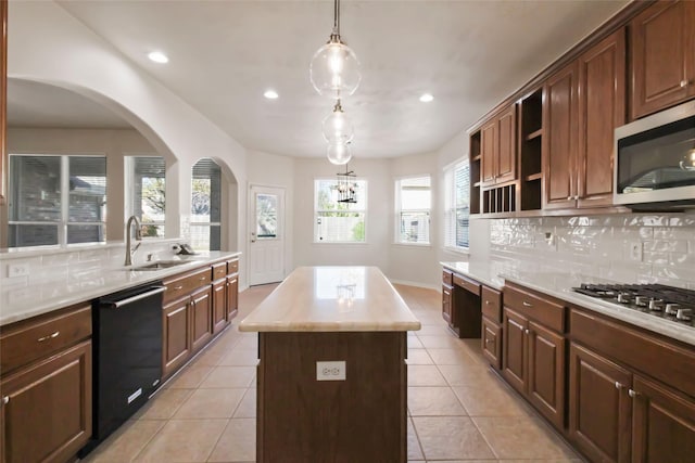 kitchen featuring sink, stainless steel appliances, a kitchen island, decorative light fixtures, and light tile patterned floors