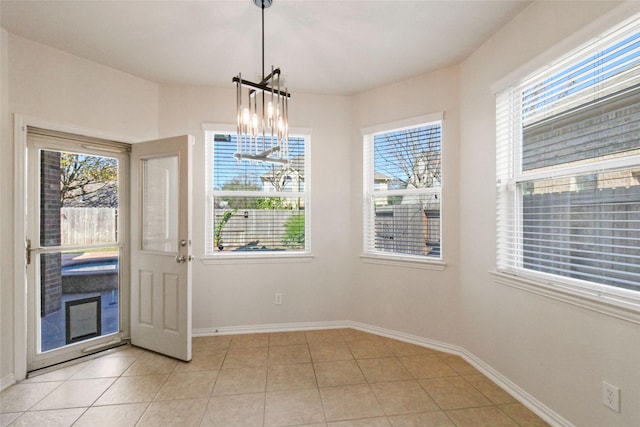 unfurnished dining area with a wealth of natural light, light tile patterned flooring, and a notable chandelier