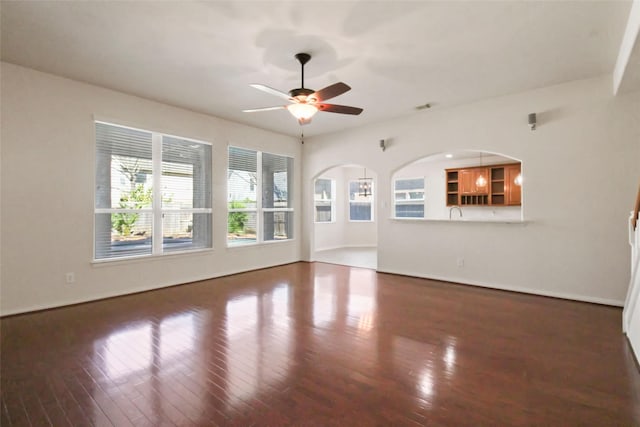 unfurnished living room with dark hardwood / wood-style flooring and ceiling fan