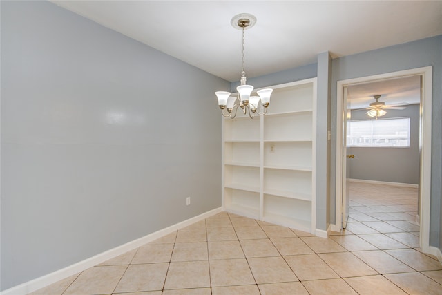 spare room featuring built in features, light tile patterned flooring, and ceiling fan with notable chandelier