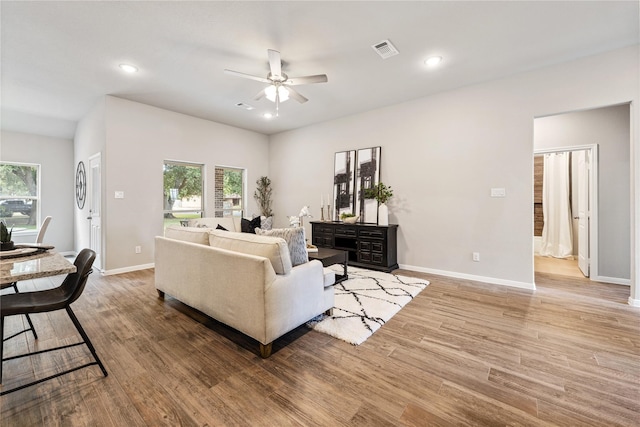 living room with light hardwood / wood-style flooring and ceiling fan