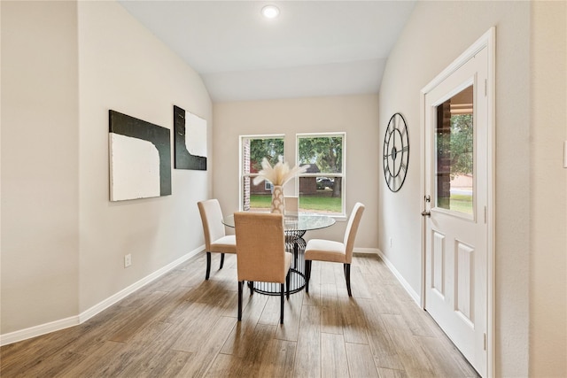 dining area with wood-type flooring and vaulted ceiling