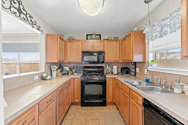 kitchen featuring light tile patterned floors, black appliances, hanging light fixtures, and sink