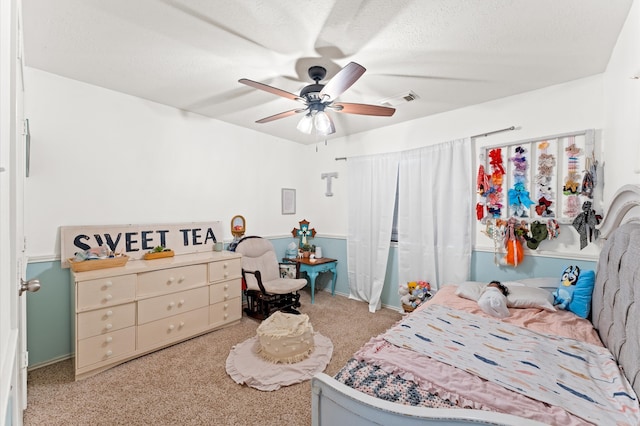 bedroom featuring a textured ceiling, light colored carpet, and ceiling fan