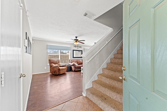 stairway with a textured ceiling, light hardwood / wood-style flooring, and ceiling fan