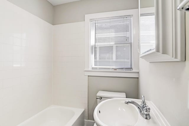 bathroom featuring toilet and tiled shower / bath