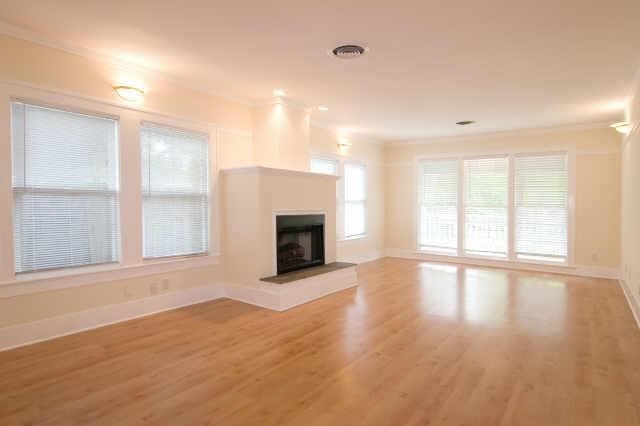 unfurnished living room featuring hardwood / wood-style flooring, ornamental molding, and plenty of natural light