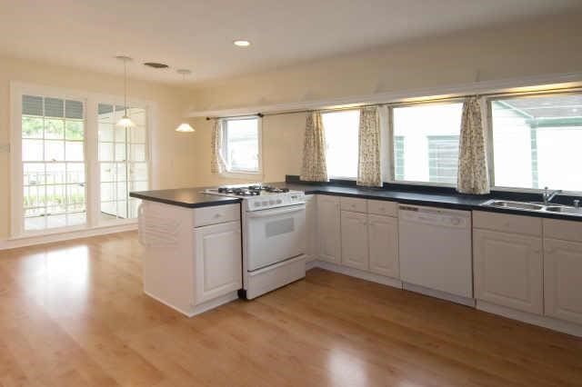 kitchen with white cabinets, light wood-type flooring, and white appliances