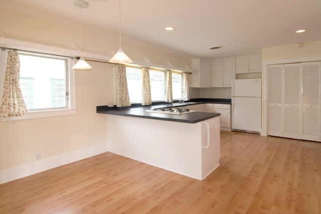 kitchen featuring light hardwood / wood-style flooring, white cabinets, white refrigerator, kitchen peninsula, and hanging light fixtures