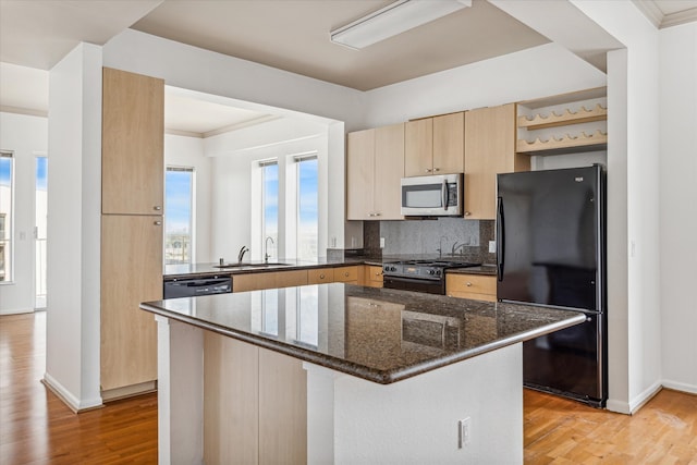 kitchen featuring dark stone countertops, light hardwood / wood-style floors, black appliances, and crown molding