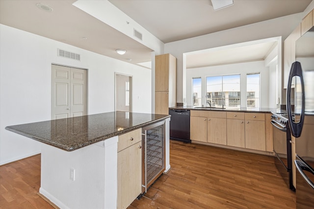 kitchen featuring dark stone countertops, wood-type flooring, light brown cabinetry, and black appliances