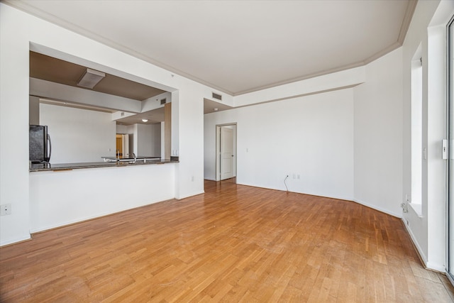 unfurnished living room featuring light hardwood / wood-style floors and crown molding