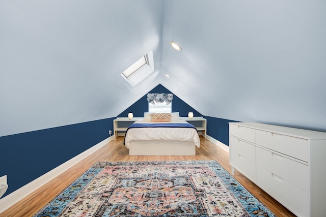 bedroom with lofted ceiling with skylight and light hardwood / wood-style flooring