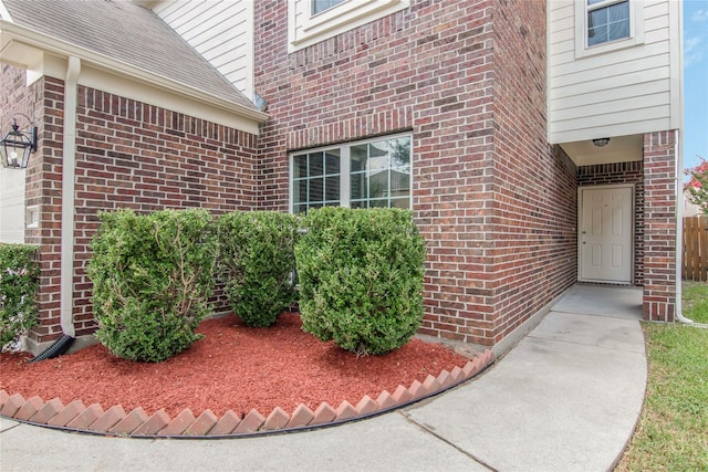 doorway to property with brick siding and roof with shingles