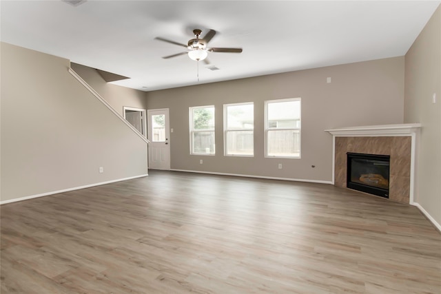 unfurnished living room with ceiling fan, a fireplace, and light hardwood / wood-style flooring