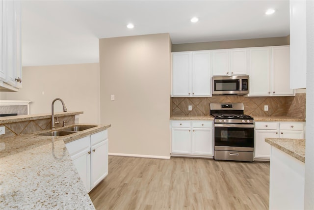 kitchen featuring light stone countertops, white cabinetry, appliances with stainless steel finishes, and a sink