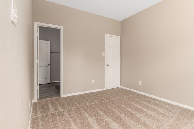 unfurnished bedroom with carpet floors, baseboards, and a walk in closet