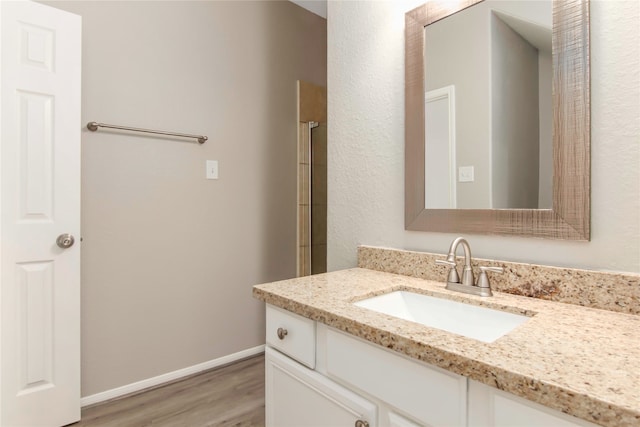 full bath with wood finished floors, vanity, and baseboards