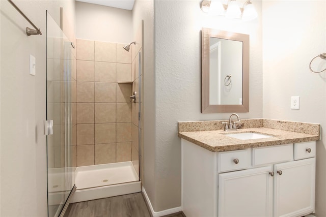 full bathroom featuring a stall shower, wood finished floors, vanity, and baseboards