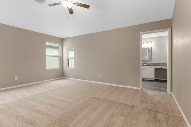 spare room with a ceiling fan, light colored carpet, and baseboards