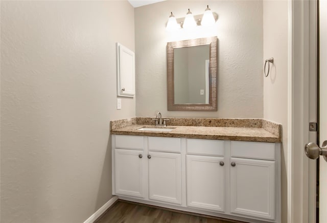 bathroom with vanity, baseboards, and wood finished floors