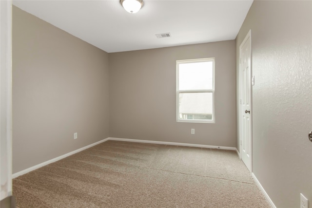 spare room with carpet, visible vents, and baseboards