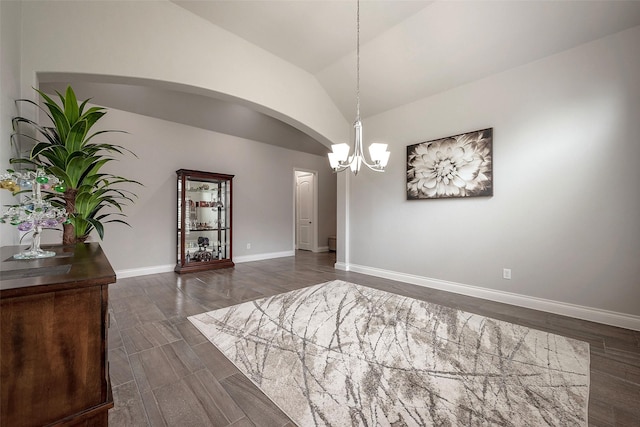 unfurnished dining area featuring dark wood-type flooring, arched walkways, baseboards, a chandelier, and vaulted ceiling