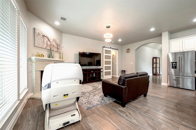 living room with visible vents, baseboards, recessed lighting, arched walkways, and a barn door