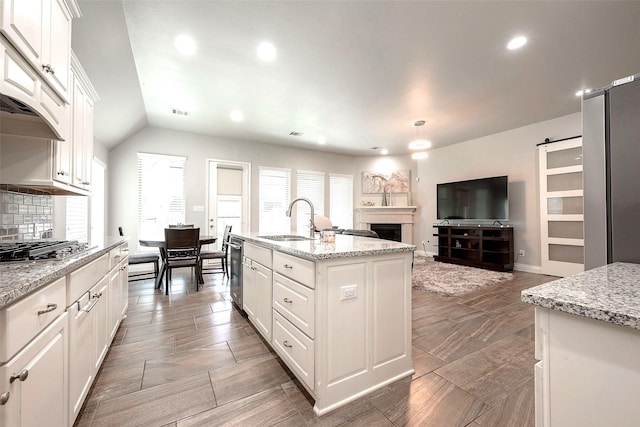 kitchen featuring a sink, white cabinetry, a barn door, stainless steel appliances, and a fireplace