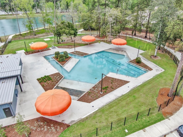 community pool with a lawn, fence, a patio, and a water view