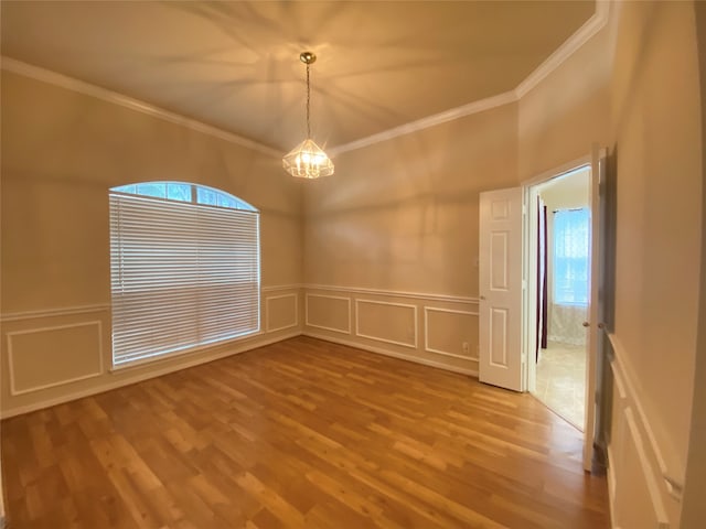 empty room with an inviting chandelier, hardwood / wood-style flooring, and crown molding