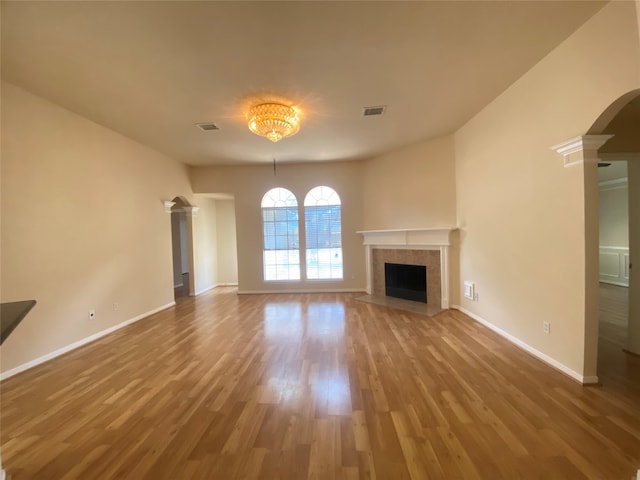 unfurnished living room with wood-type flooring and a tiled fireplace