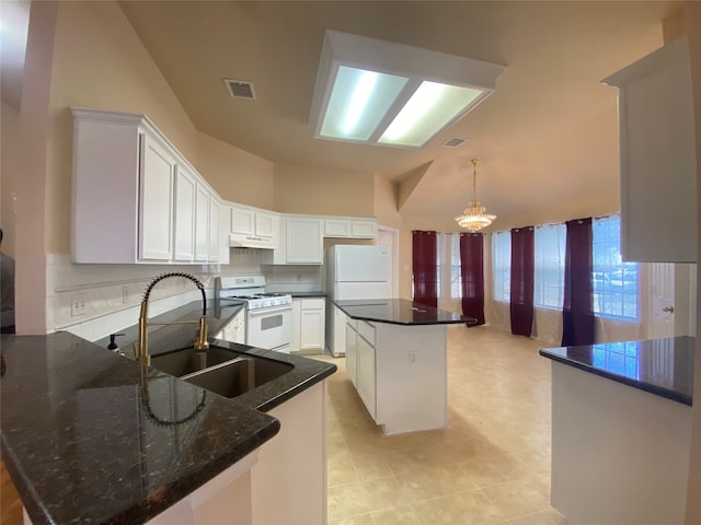 kitchen with white cabinets, white appliances, a kitchen island, and sink