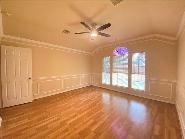 empty room with ornamental molding, vaulted ceiling, ceiling fan, and hardwood / wood-style floors