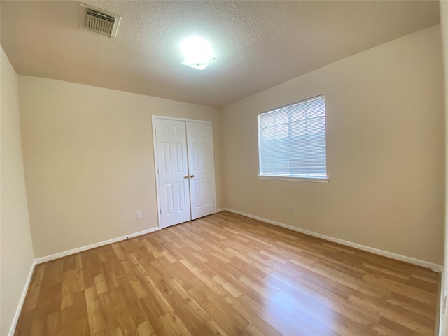 spare room with light hardwood / wood-style flooring and a textured ceiling