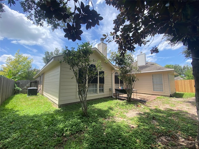 rear view of property featuring a yard and central AC unit