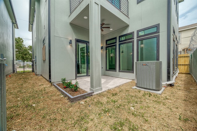 rear view of property featuring ceiling fan, central air condition unit, a yard, and a patio area