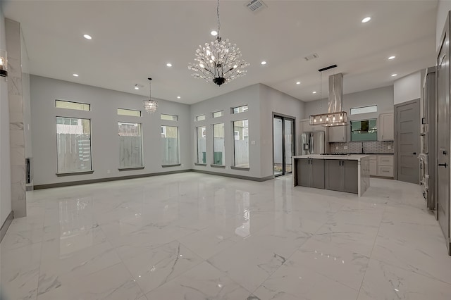 interior space featuring appliances with stainless steel finishes, decorative light fixtures, island exhaust hood, light tile patterned flooring, and a center island