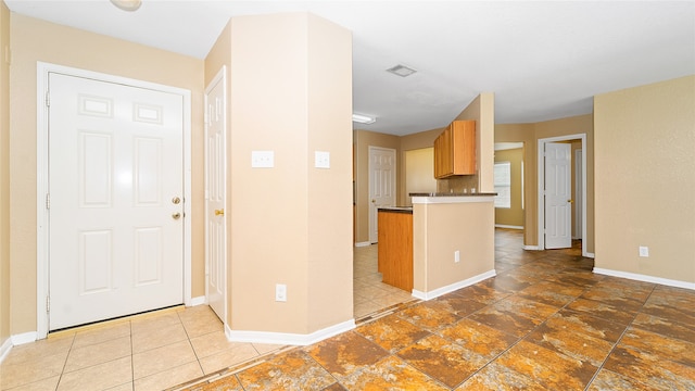 kitchen featuring kitchen peninsula, dark tile patterned flooring, and decorative backsplash