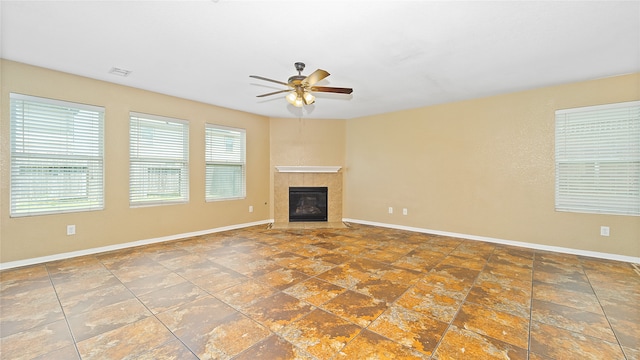 unfurnished living room featuring dark tile patterned flooring, a tiled fireplace, and ceiling fan