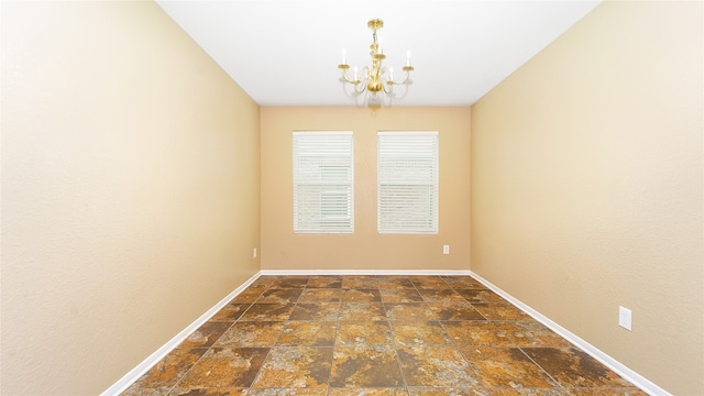 empty room with a notable chandelier and dark tile patterned floors