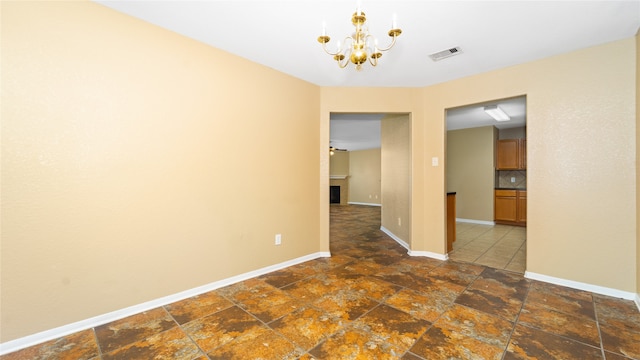 tiled empty room featuring a notable chandelier