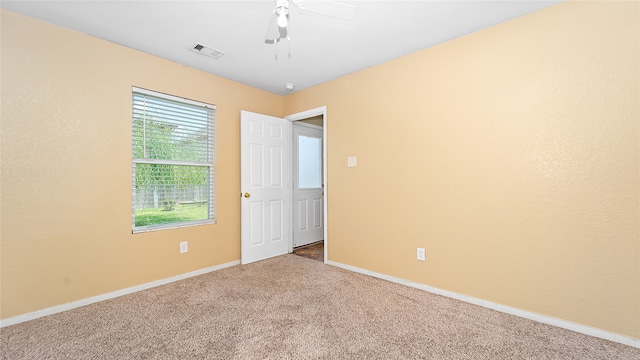 empty room featuring ceiling fan and carpet