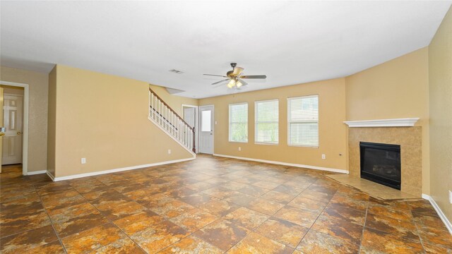 unfurnished living room featuring a tile fireplace, tile patterned floors, and ceiling fan