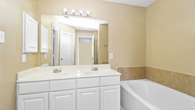 bathroom featuring a washtub and dual bowl vanity