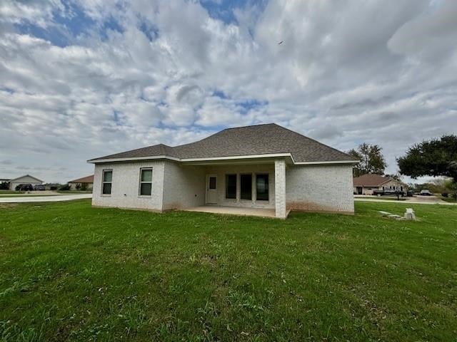 rear view of property featuring a lawn and a patio area