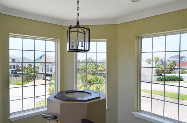 interior space featuring a healthy amount of sunlight, crown molding, and a chandelier